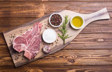 Madde ile ham sığır eti biftek T kemik. Porterhouse kesme tahtası üzerinde .