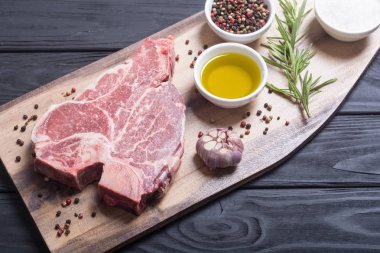 Madde ile ham sığır eti biftek T kemik. Porterhouse kesme tahtası üzerinde .