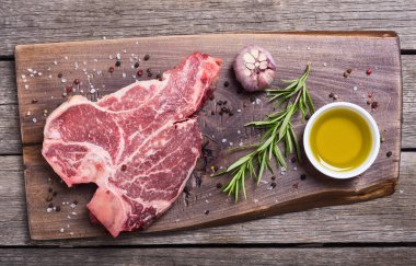 Madde ile ham sığır eti biftek T kemik. Porterhouse kesme tahtası üzerinde .