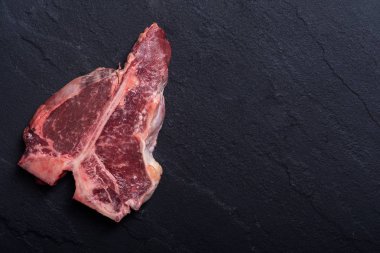 Porterhouse biftek et çiğ biftek. T-Bone rustik arka plan üzerinde