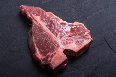 Porterhouse biftek et çiğ biftek. T-Bone rustik arka plan üzerinde