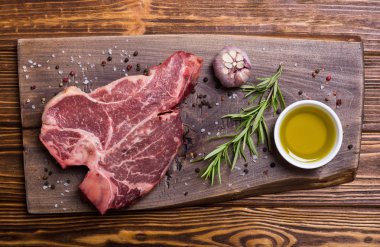 Madde ile ham sığır eti biftek T kemik. Porterhouse kesme tahtası üzerinde .