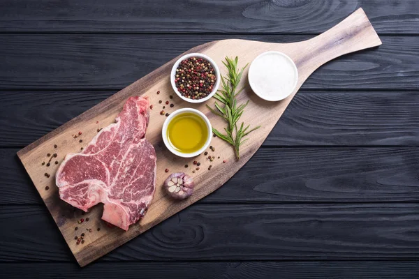 Porterhouse biftek et çiğ biftek. T-Bone rustik arka plan üzerinde