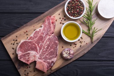 Madde ile ham sığır eti biftek T kemik. Porterhouse kesme tahtası üzerinde .