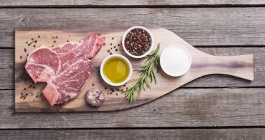 Madde ile ham sığır eti biftek T kemik. Porterhouse kesme tahtası üzerinde .