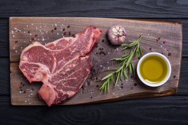 Madde ile ham sığır eti biftek T kemik. Porterhouse kesme tahtası üzerinde .