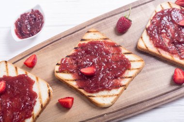 Rustik ahşap zemin üzerine çilek reçeli ile tost