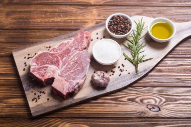 Madde ile ham sığır eti biftek T kemik. Porterhouse kesme tahtası üzerinde .