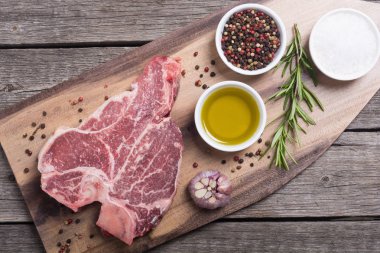 Madde ile ham sığır eti biftek T kemik. Porterhouse kesme tahtası üzerinde .