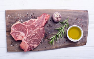Madde ile ham sığır eti biftek T kemik. Porterhouse kesme tahtası üzerinde .