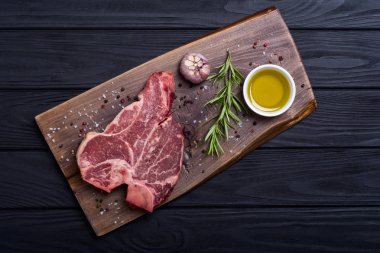 Madde ile ham sığır eti biftek T kemik. Porterhouse kesme tahtası üzerinde .