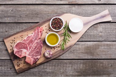 Madde ile ham sığır eti biftek T kemik. Porterhouse kesme tahtası üzerinde .