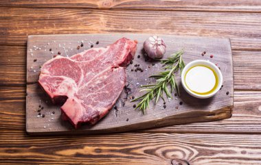 Madde ile ham sığır eti biftek T kemik. Porterhouse kesme tahtası üzerinde .