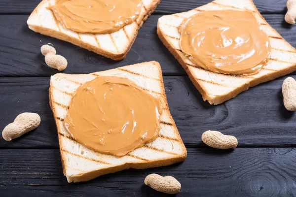 Peanut butter sandwiches or toasts on wooden background