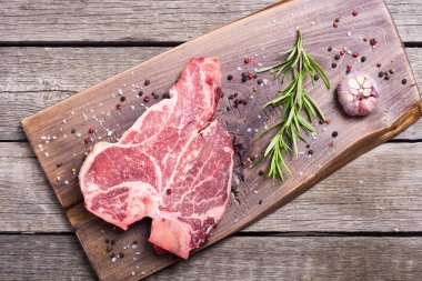 Madde ile ham sığır eti biftek T kemik. Porterhouse kesme tahtası üzerinde .