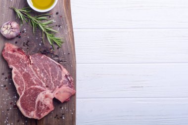 Madde ile ham sığır eti biftek T kemik. Porterhouse kesme tahtası üzerinde .