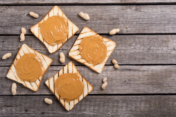 Peanut butter sandwiches or toasts on wooden background