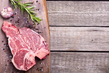 Madde ile ham sığır eti biftek T kemik. Porterhouse kesme tahtası üzerinde .