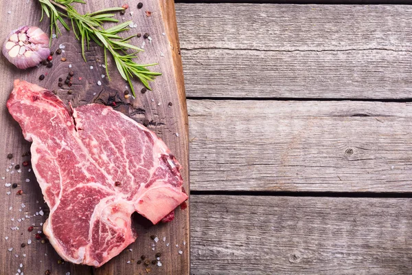 Madde ile ham sığır eti biftek T kemik. Porterhouse kesme tahtası üzerinde .