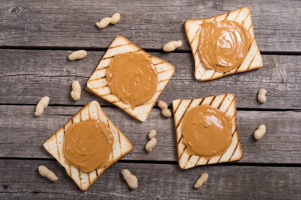 Peanut butter sandwiches or toasts on wooden background