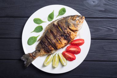 Kızarmış balık dorado limon, domates ve ıspanak ile. Deniz gıda arka plan