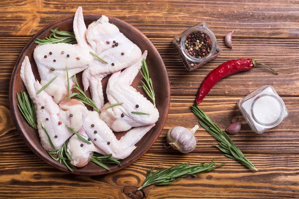 Chicken raw wings with rosemary , garlic , pepper and salt . Ingredient for preparation