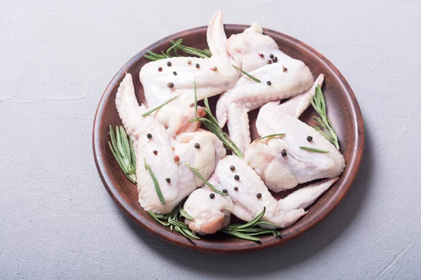 Chicken raw wings with rosemary , garlic , pepper and salt . Ingredient for preparation