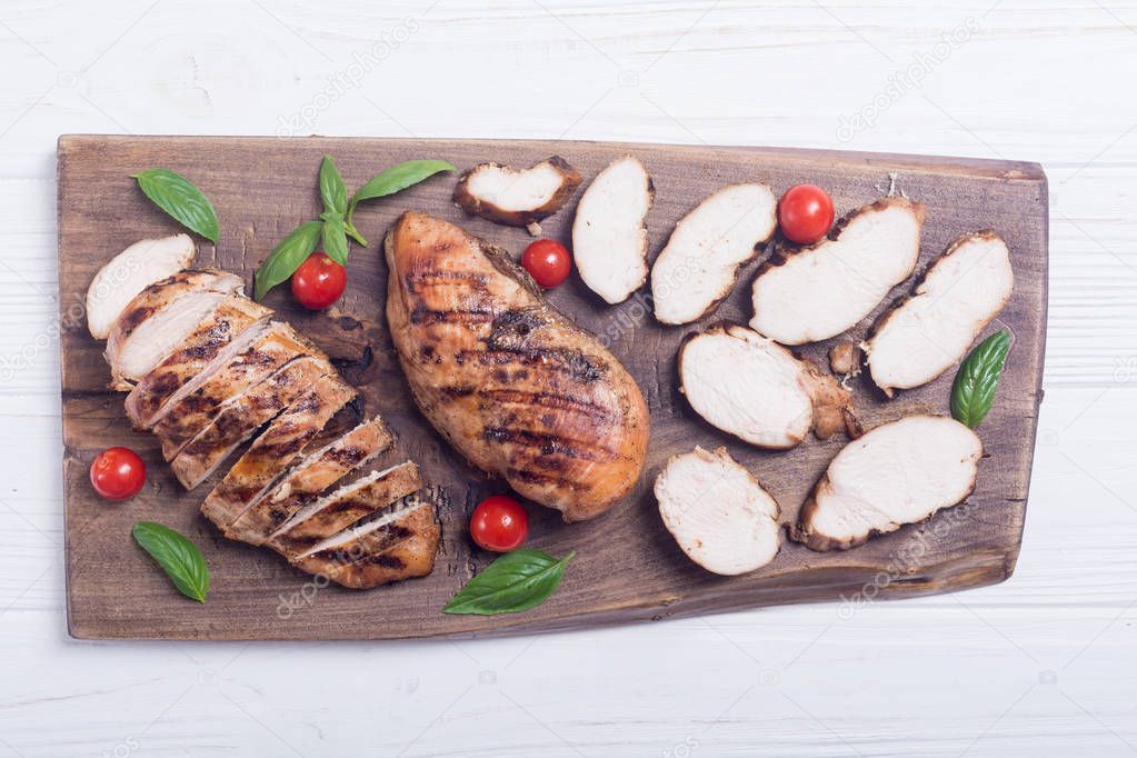 Grilled chicken breast ( fillet ) with basil and tomatoes . BBQ background