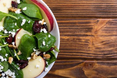 Elma, peynir, ceviz ve kurutulmuş kızılcık sonbahar ıspanak salatası. Sağlıklı vejetaryen yemek
