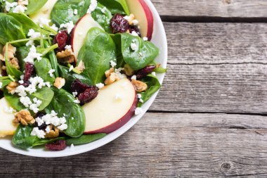 Elma, peynir, ceviz ve kurutulmuş kızılcık sonbahar ıspanak salatası. Sağlıklı vejetaryen yemek