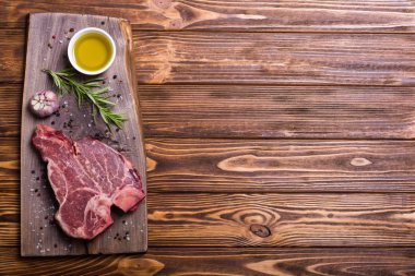 Madde ile ham sığır eti biftek T kemik. Porterhouse kesme tahtası üzerinde .