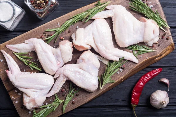 Chicken raw wings with rosemary , garlic , pepper and salt . Ingredient for preparation