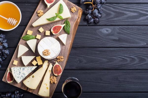 Cheeseboard with cheese brie , parmesan , camembert and dorblu . Food on wooden board