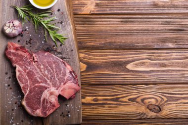 Madde ile ham sığır eti biftek T kemik. Porterhouse kesme tahtası üzerinde .