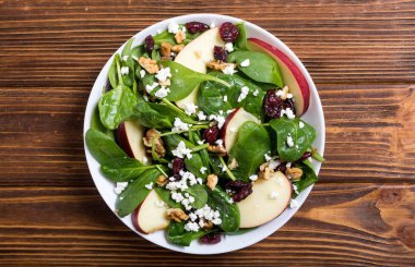 Elma, peynir, ceviz ve kurutulmuş kızılcık sonbahar ıspanak salatası. Sağlıklı vejetaryen yemek
