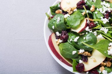 Elma, peynir, ceviz ve kurutulmuş kızılcık sonbahar ıspanak salatası. Sağlıklı vejetaryen yemek