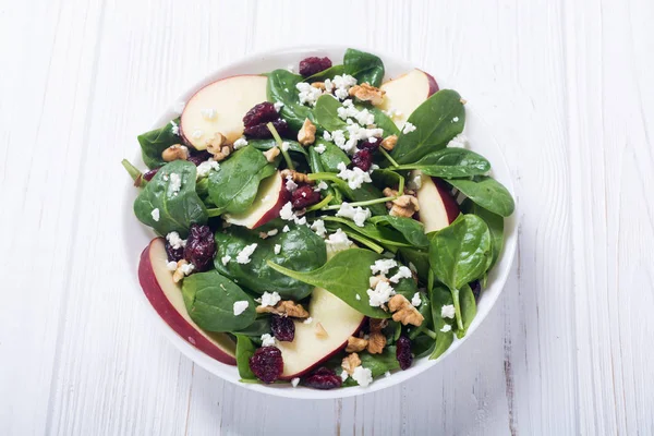 Autumn spinach salad with apple , cheese , walnut and dried cranberry . Healthy vegetarian food