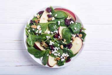 Elma, peynir, ceviz ve kurutulmuş kızılcık sonbahar ıspanak salatası. Sağlıklı vejetaryen yemek