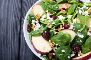 Elma, peynir, ceviz ve kurutulmuş kızılcık sonbahar ıspanak salatası. Sağlıklı vejetaryen yemek
