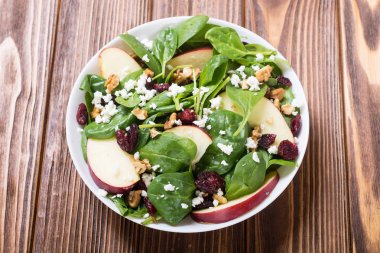 Elma, peynir, ceviz ve kurutulmuş kızılcık sonbahar ıspanak salatası. Sağlıklı vejetaryen yemek