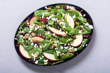 Elma, peynir, ceviz ve kurutulmuş kızılcık sonbahar ıspanak salatası. Sağlıklı vejetaryen yemek