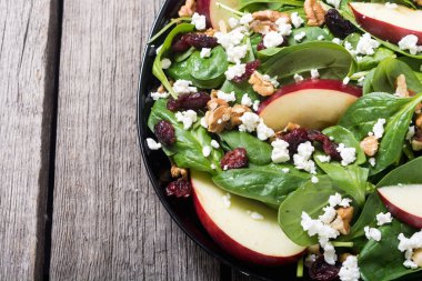 Elma, peynir, ceviz ve kurutulmuş kızılcık sonbahar ıspanak salatası. Sağlıklı vejetaryen yemek
