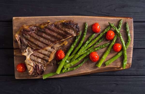 Grilled T-bone steak with asparagus and cherry tomatoes . T bone beef