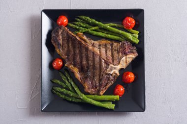 Kuşkonmaz ve kiraz domates ile ızgara T-kemik biftek 