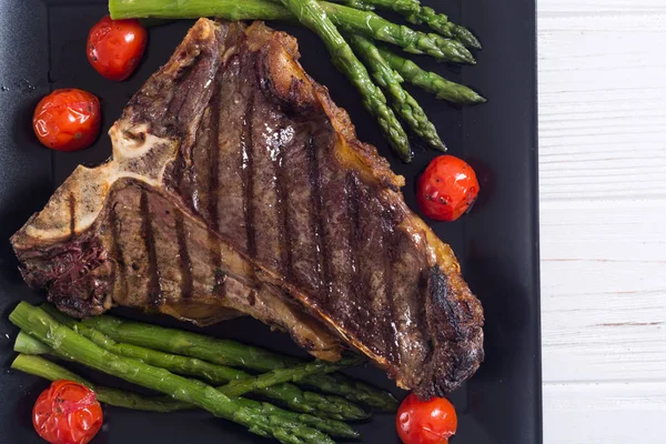 Grilled T-bone steak with asparagus and cherry tomatoes — Stock Photo, Image