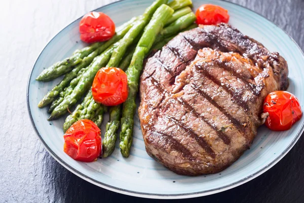 Côtelette de bœuf grillée avec tomates cerises et asperges — Photo