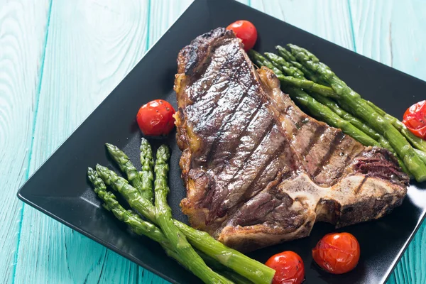 Grilled T-bone steak with asparagus and cherry tomatoes — Stock Photo, Image