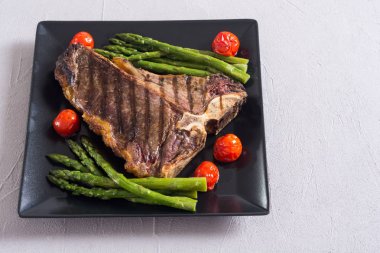 Kuşkonmaz ve kiraz domates ile ızgara T-kemik biftek 