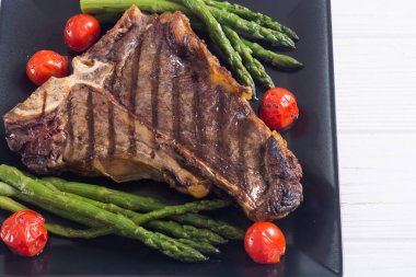 Kuşkonmaz ve kiraz domates ile ızgara T-kemik biftek 