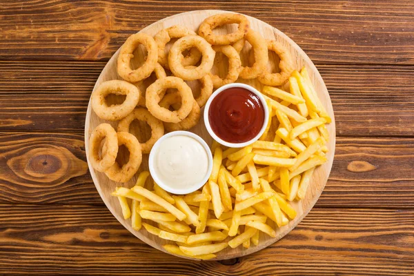 Patatine fritte e anelli di cipolla con salse — Foto Stock